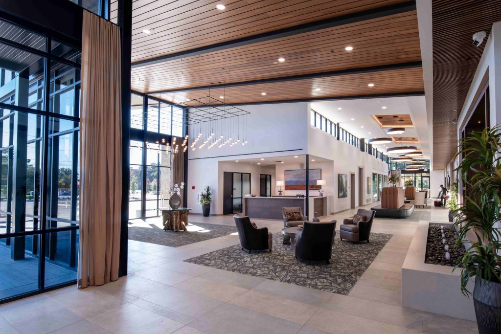 Modern lobby with travertine walls and wood paneling, an example of identity-driven interiors shaped by material and light.